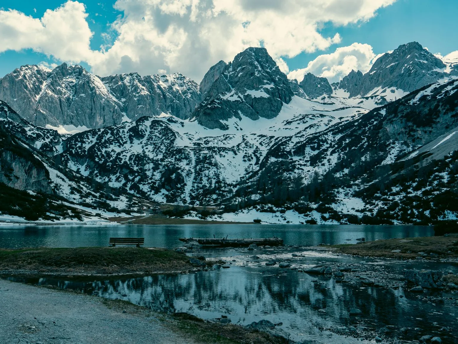 Montanhas nevadas erguem-se sobre um lago alpino refletor.