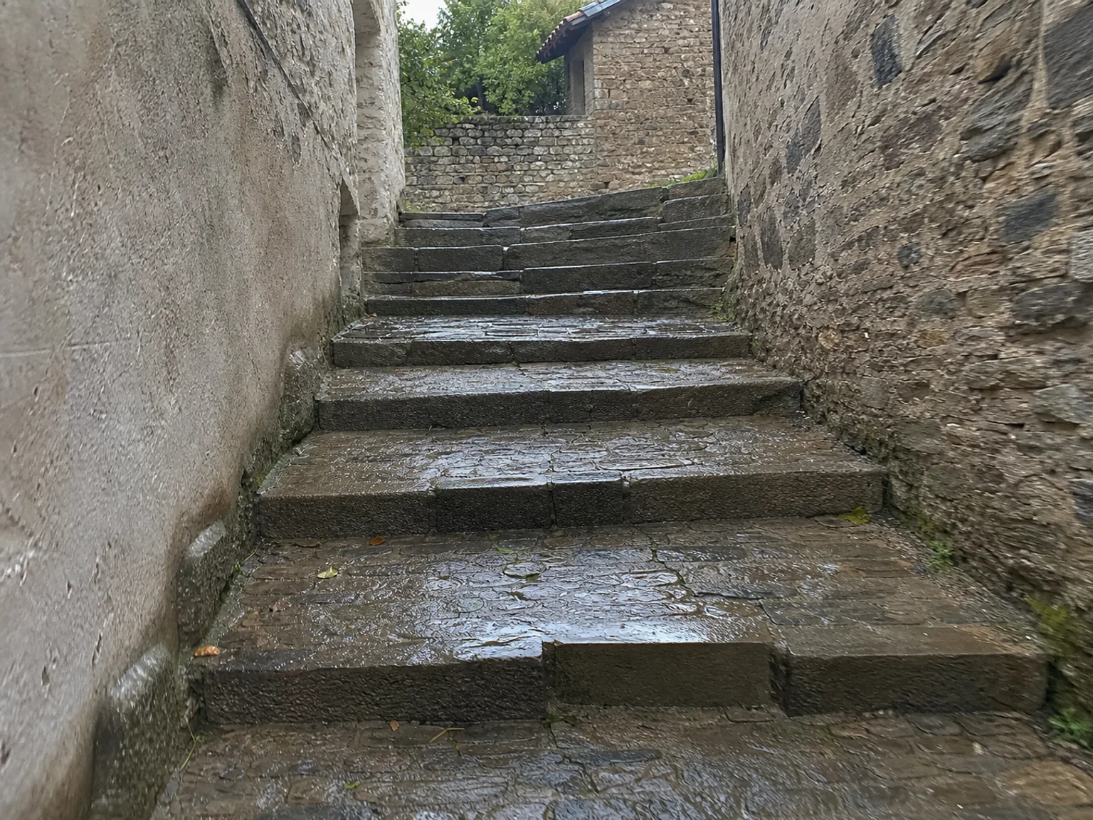 Escalones de piedra suben por un pasaje estrecho entre muros rugosos.