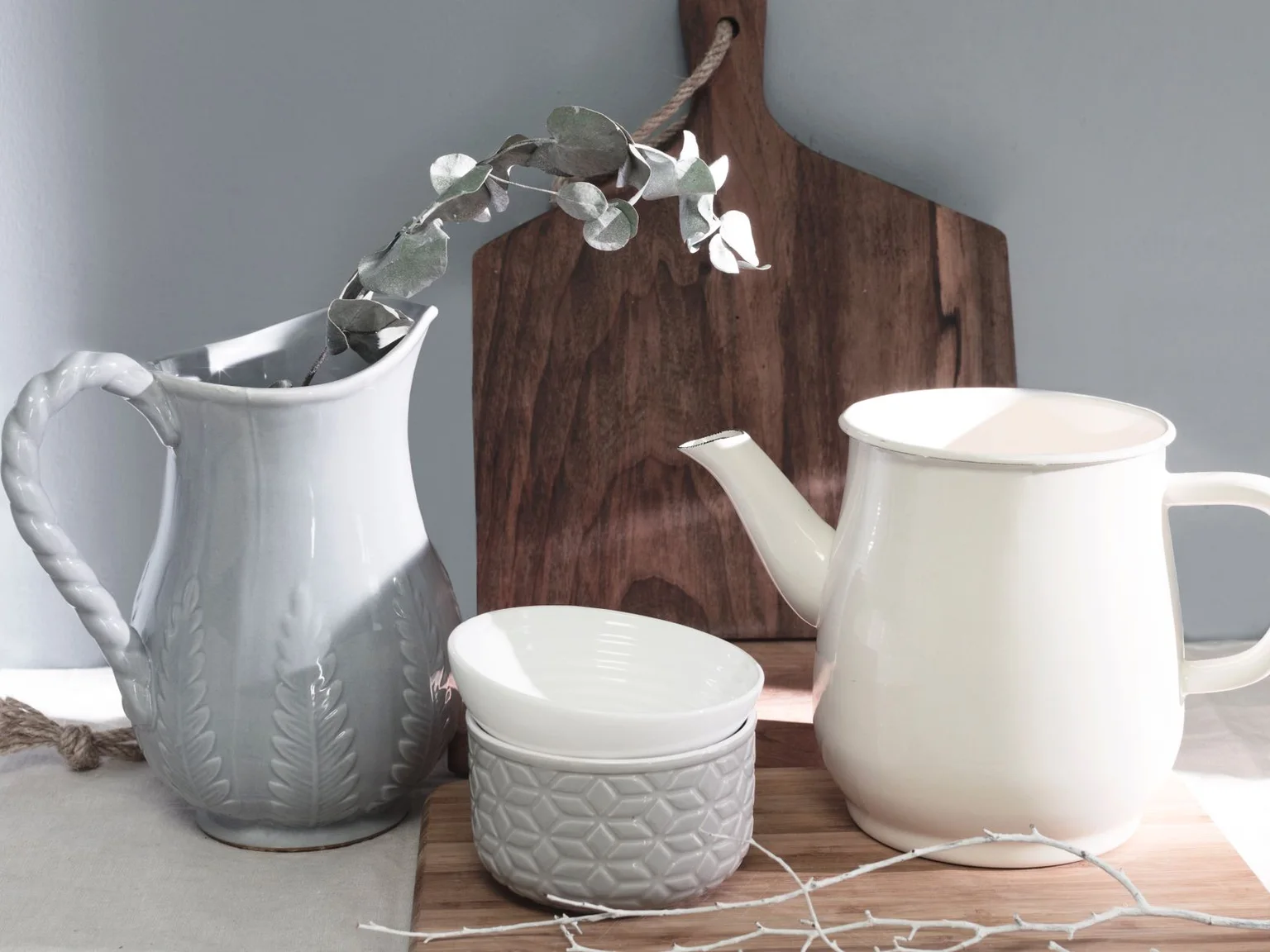Jarras e tacas de ceramica branca estao colocadas sobre uma mesa.