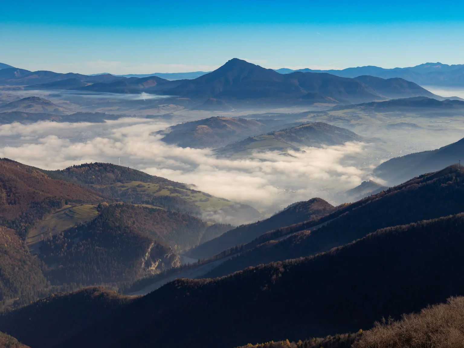 Cristas de montanha erguem-se sobre um vale cheio de nuvens baixas.